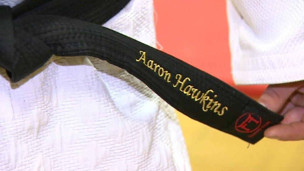 Aaron Hawkins holding his blackbelt with his name on it