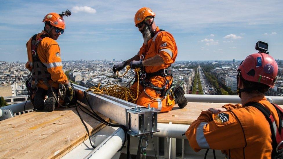 Workers prepare the assembly of the Arc de Triomphe installation