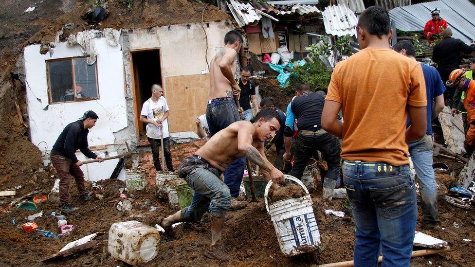 People and rescue agencies look for bodies in a destroyed area after mudslides, caused by heavy rains leading several rivers to overflow, pushing sediment and rocks into buildings and roads, in Manizales