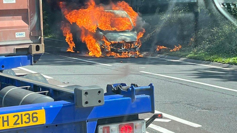 A van engulfed in flames on a main road