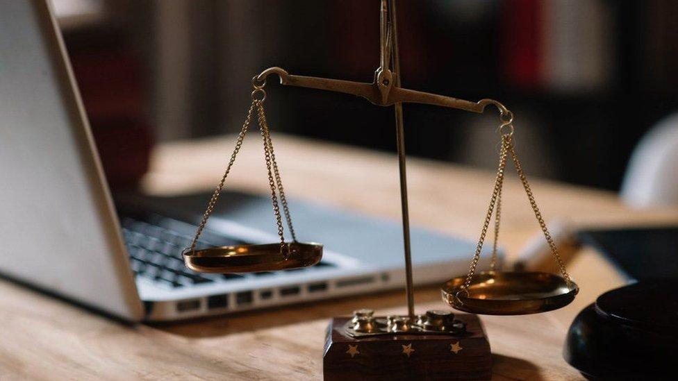 Scale of justice in front of computer on desk