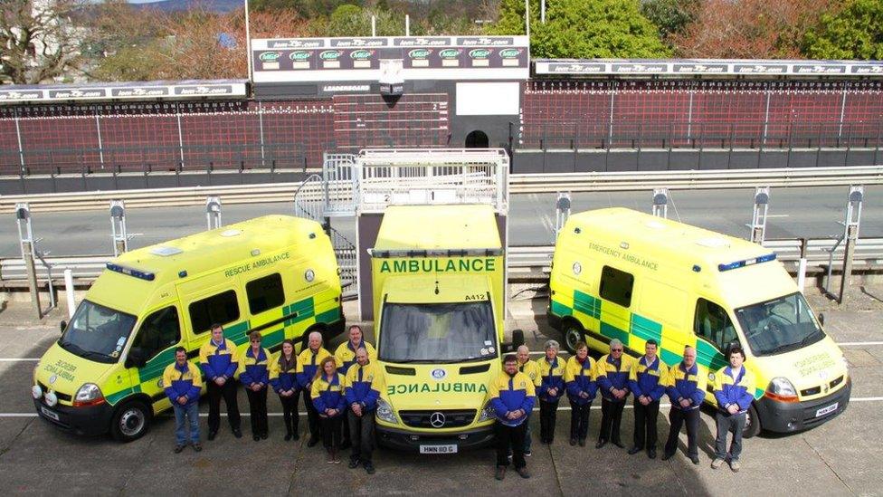 Volunteers standing in front of three ambulances