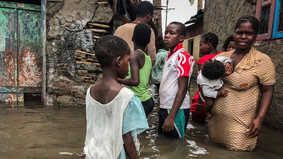 A family stand outside their flooded house