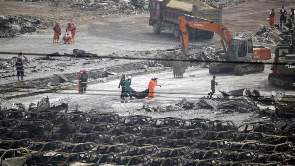 Firefighters carry the body of a victim from the site of the explosions at the Binhai new district, Tianjin