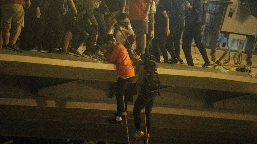 Protesters lower themselves down a rope from a bridge to a highway to escape Polytechnic University campus