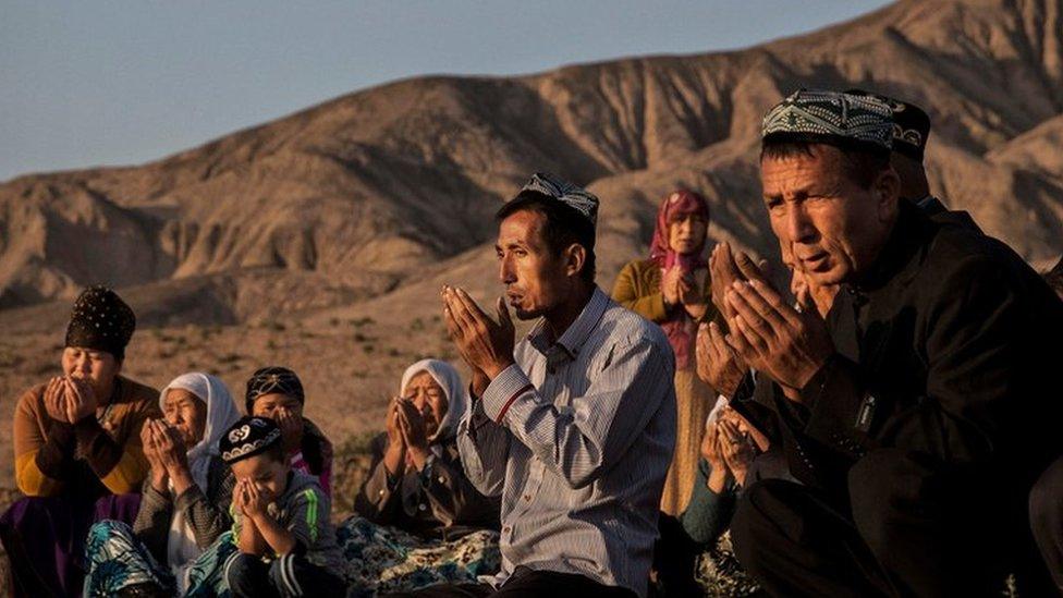 A Uyghur family pray at the grave of a loved one - 2016