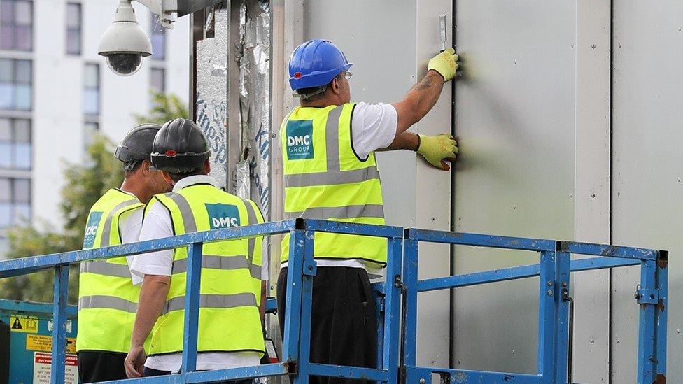 Workers removing cladding