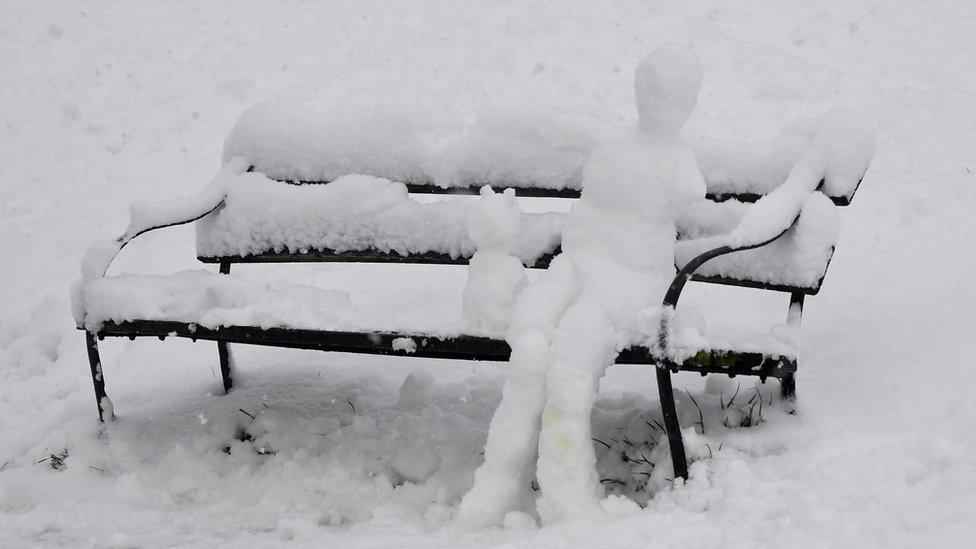 A snowman and snow-cat sat on a bench in Bristol.