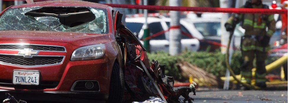 A car shows the damage after it was hit by a small plane that crashed into a strip mall parking lot in Santa Ana