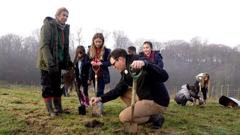 Children and adults planting trees