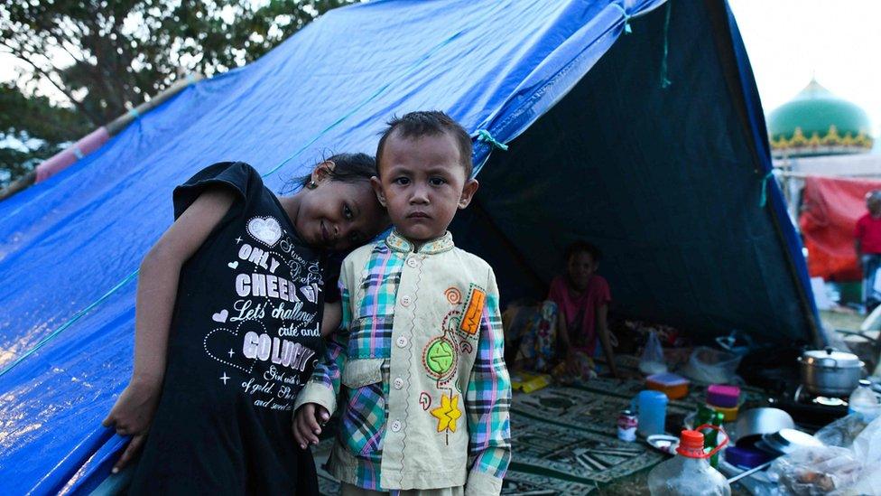 Children pose in front of a tent on a field of a mosque where they took refuge in Palu