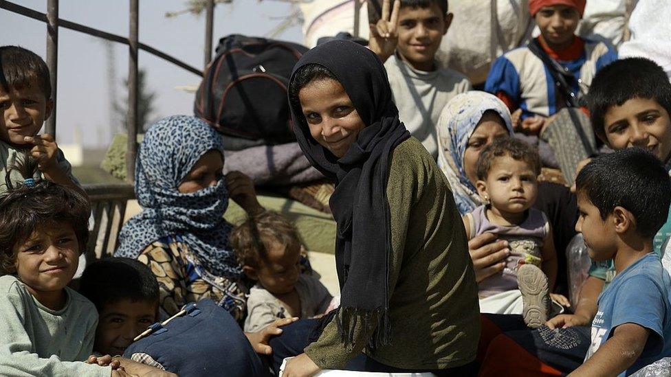 Syrian children sit on the back of a pick-up truck in the northern Syrian town of Manbij as civilians go back to their homes on 14 August 2016
