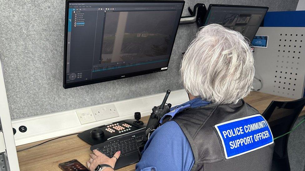 A police officer looking at CCTV camera footage in the van