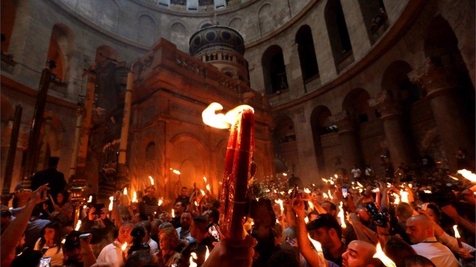 Orthodox Christians holding candles aloft in the Church of the Holy Sepulchre in Jerusalem