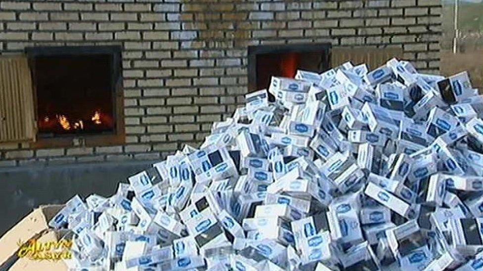 A pile of cigarette packs next of a fiery furnace