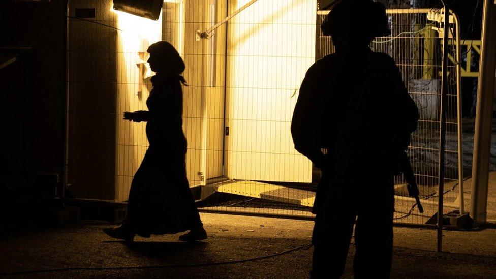 A woman walks past an Israeli soldier