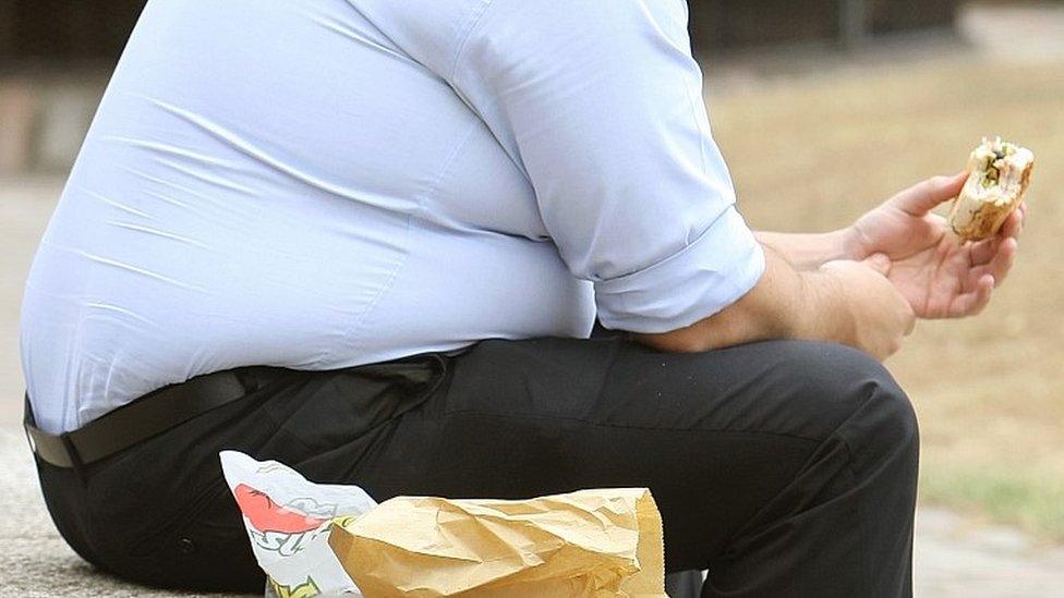 Overweight man easting a sandwich