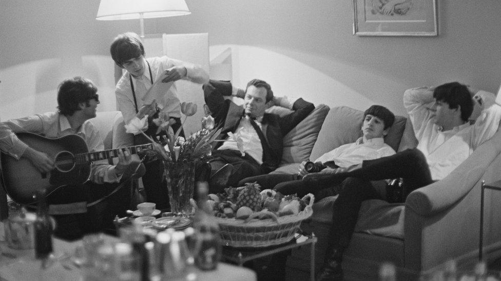 John Lennon, George Harrison, Brian Epstein, Ringo Starr and Paul McCartney relaxing on a sofa