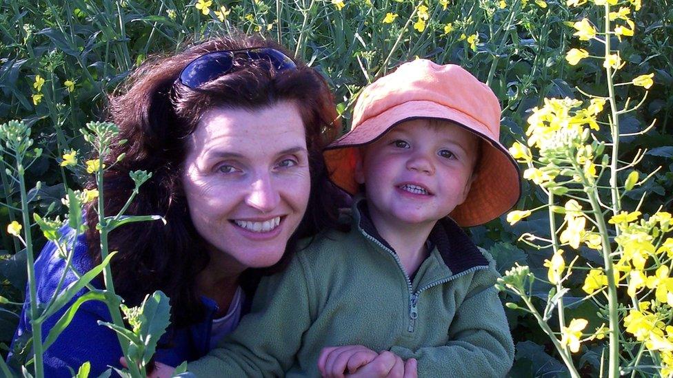 Caroline Welsh and her young son, Angus, on a farm surrounded by yellow crop