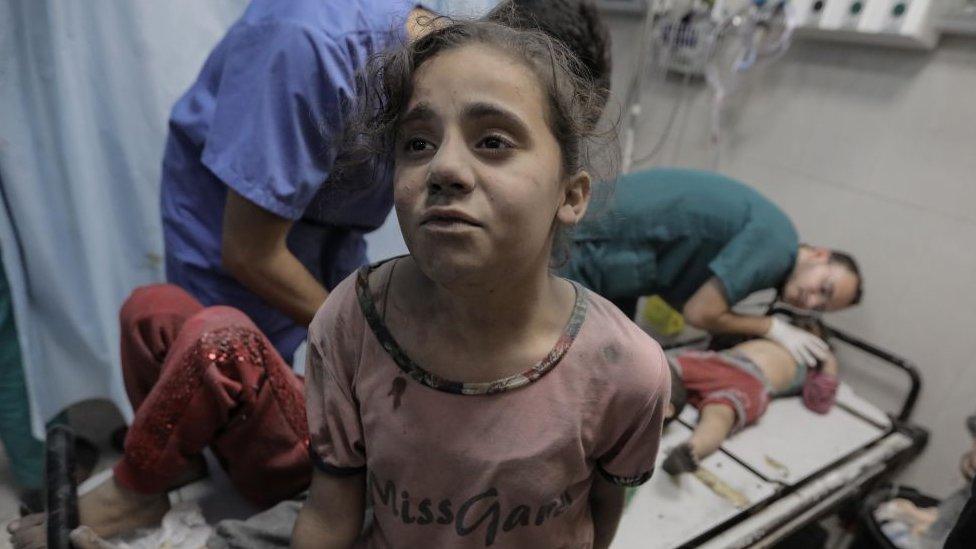 little girl covered in dust standing in front of a hospital bed at Nasser Medical Hospital on November 16, 2023 in Khan Yunis, Gaza.