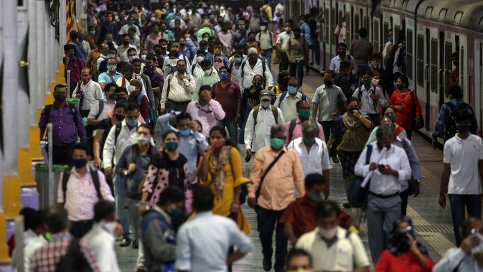 People walking along a train platform in Mumbai