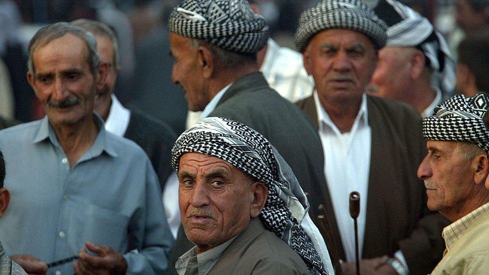 Iraqi Kurds sit in a street in Mosul on 24 October 2002