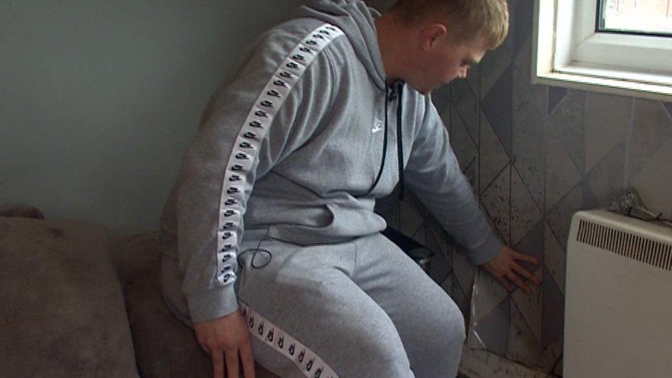 A man inspects mould on a wall