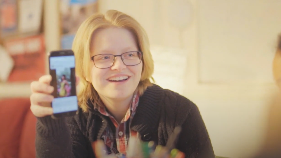 Young woman holding phone up showing photo on social media