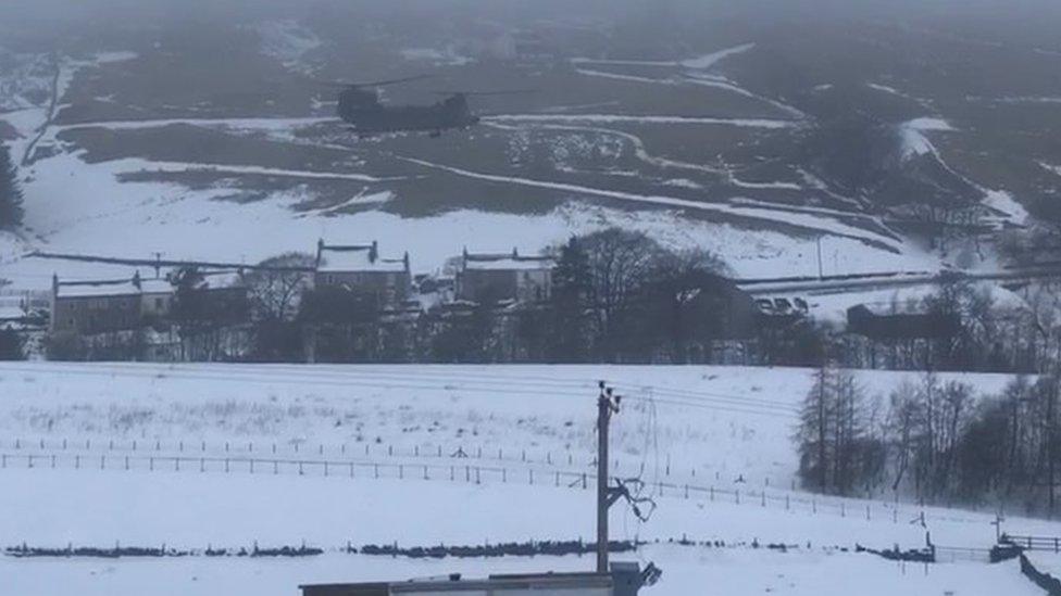 Chinook helicopter flying over snowy ground