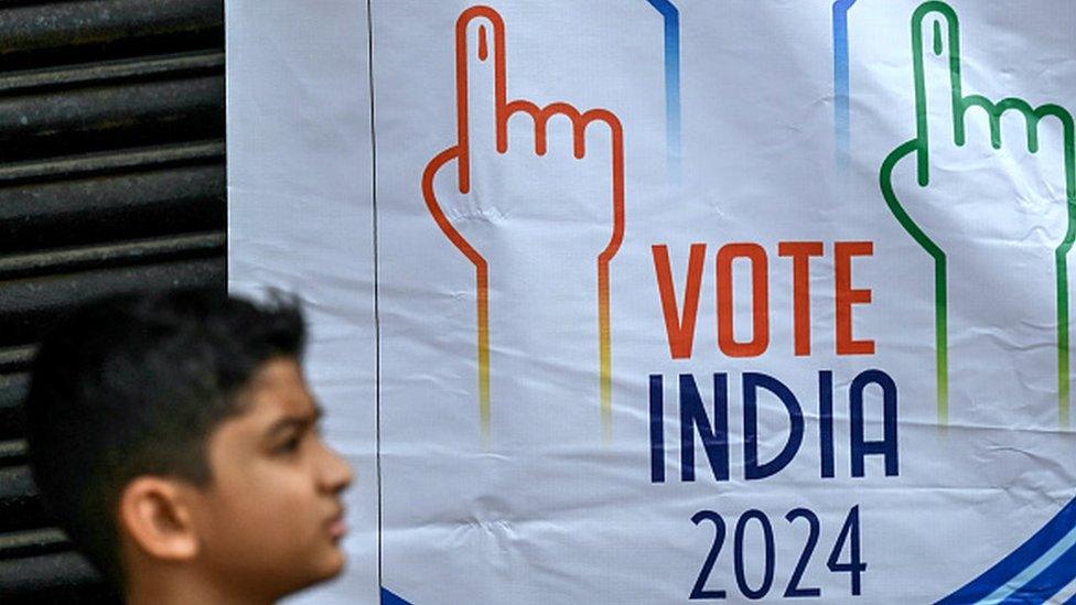 A boy walks past a banner during a students rally to create awareness about the importance of voting