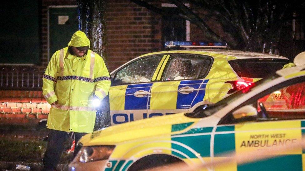 Policeman standing between emergency crew vehicles