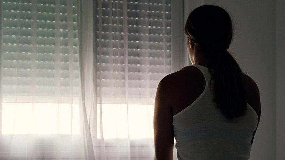 Stock photo of an abused woman sitting on her bed looking out the window