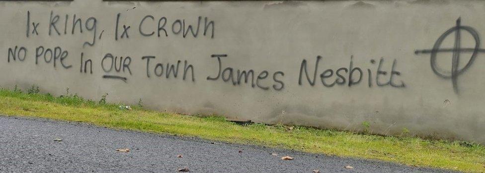 Graffiti painted on a wall, reading: 1x king, 1x crown, no Pope in our town, James Nesbitt