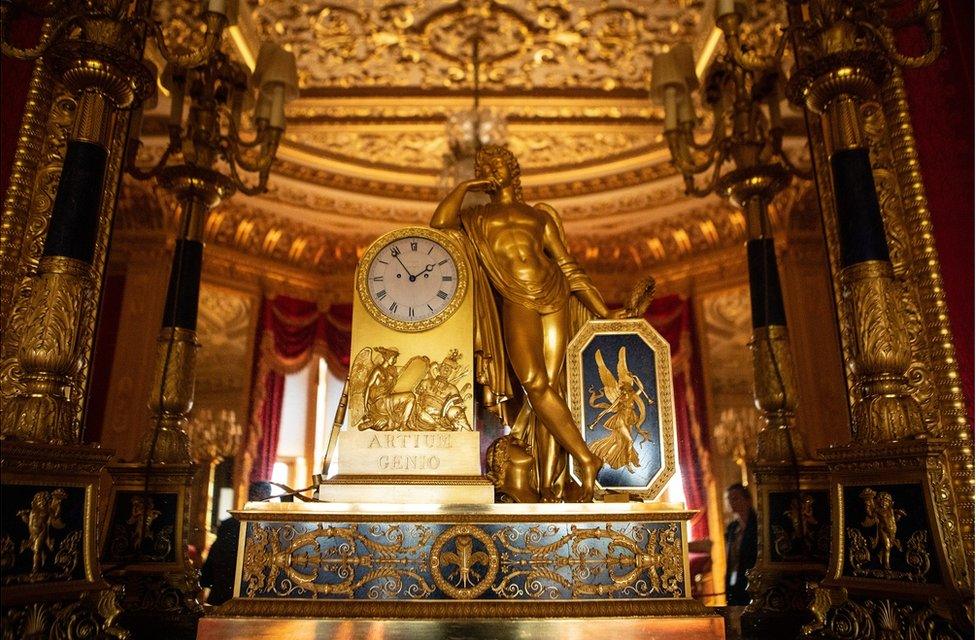 A beautiful clock on a mantelpiece that features the Greek god Apollo