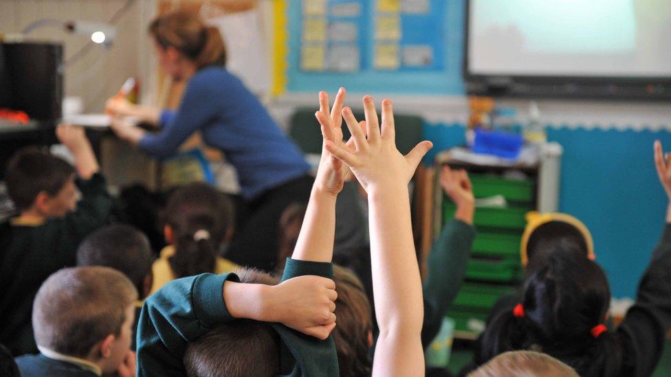 Children raise their hands at primary school