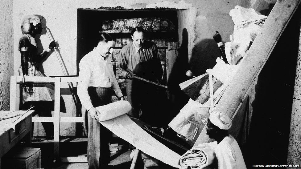 British archaeologists Howard Carter (1874 - 1939) (left) and Arthur Callender (died 1937) carry out the systematic removal of objects from the antechamber of the tomb of Pharaoh Tutankhamen, better known as King Tut, with the assistance of an Egyptian laborer, Valley of the Kings, Thebes, Egypt, 1923