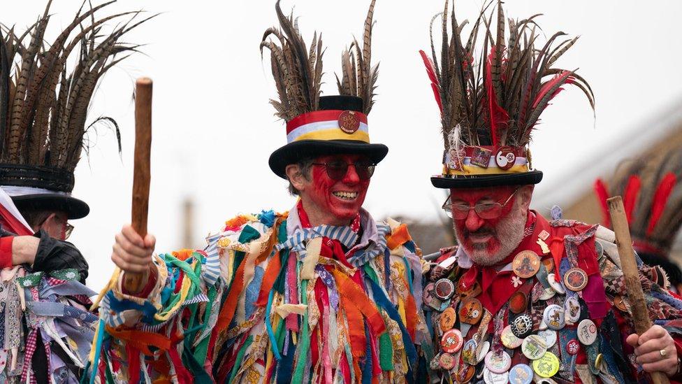 Morris dancers with faces painted red and feather headdress