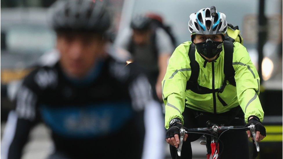 A woman wearing a face mask cycles through Westminster