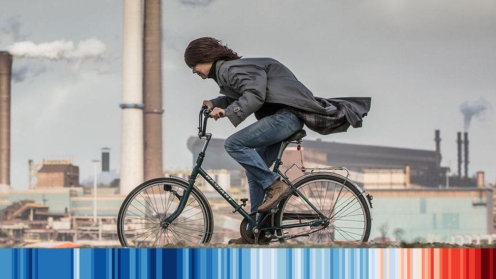 woman on bike cycling past a factory