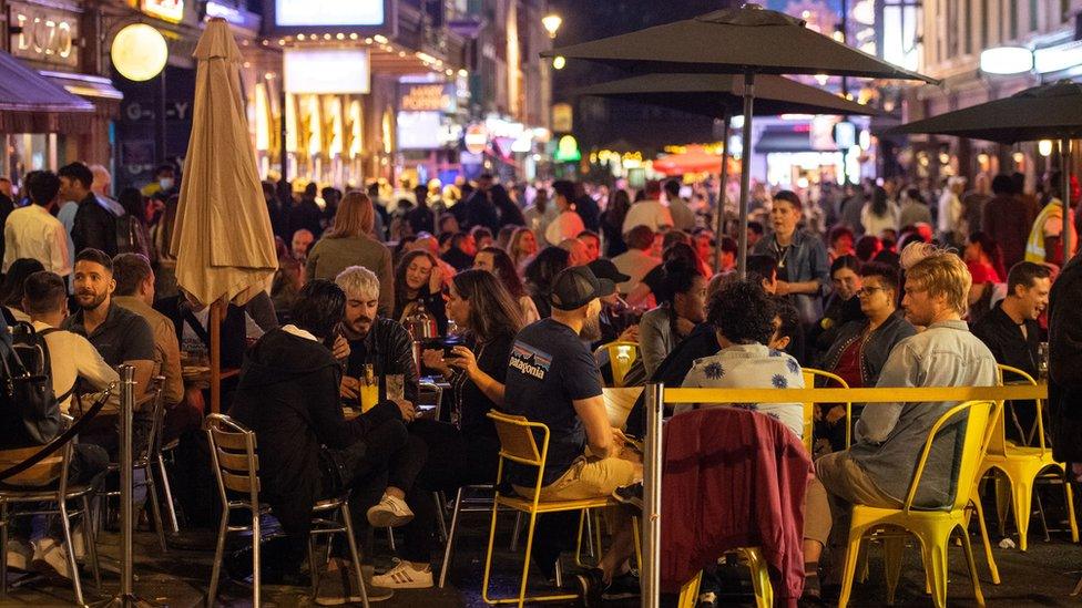 People eating and drinking outside restaurants on Old Compton St during the pandemic