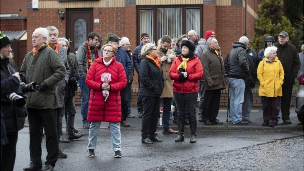 Thistle fans wait for the funeral cortege of Euromillions winner Colin Weir to pass Partick Thistle's Firhill Stadium