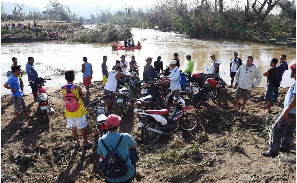 Residents wait for their turn to cross a river after a bridge was destroyed by Haima in a village in Penablanca town, Cagayan province, north of Manila, 21 October 2016.