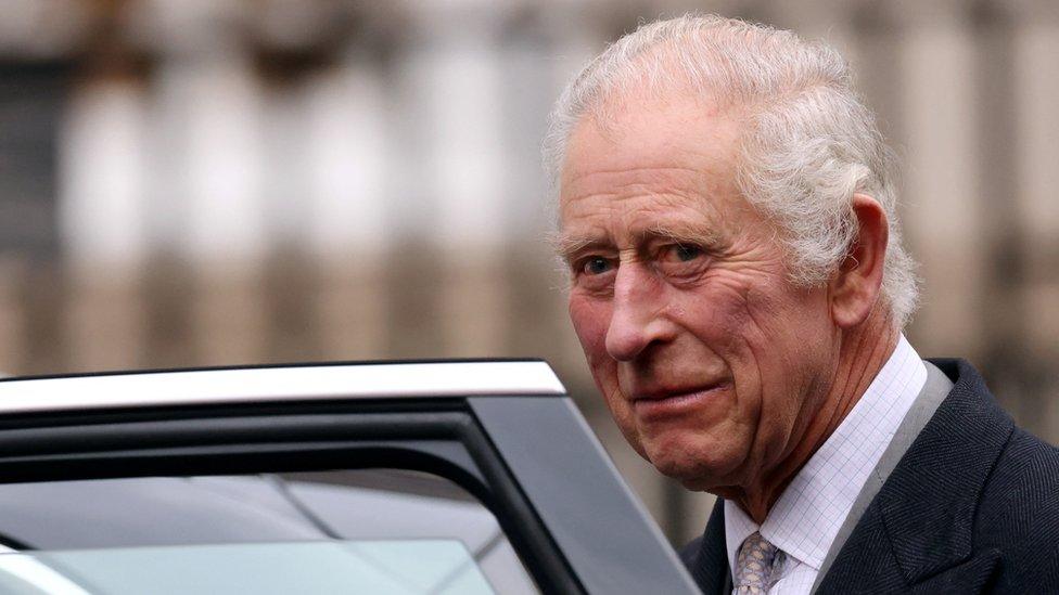 King Charles beside an open car door.