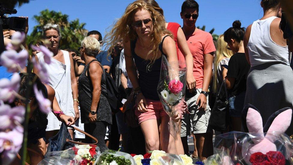 A woman lays flowers near the scene of the attack in Nice