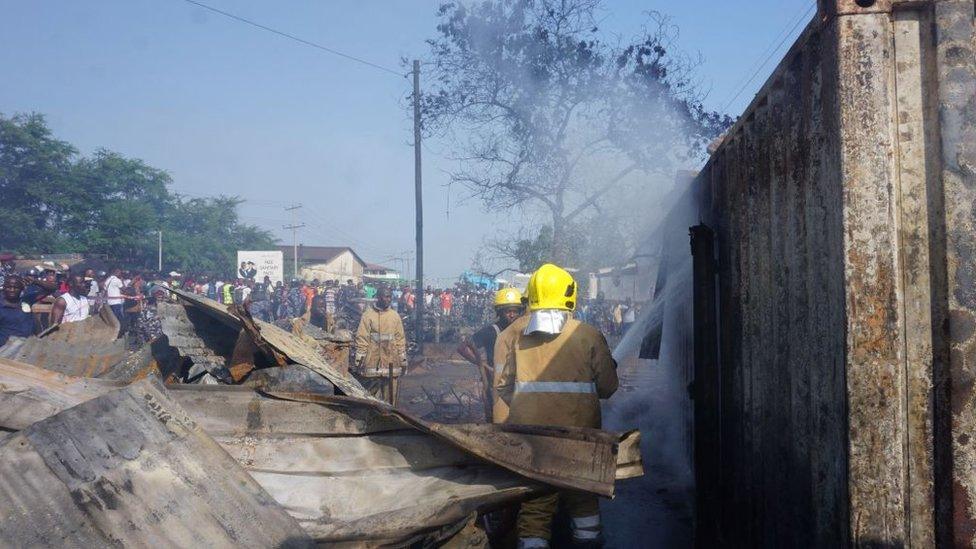 Firefighters douse a container with water on Saturday morning.