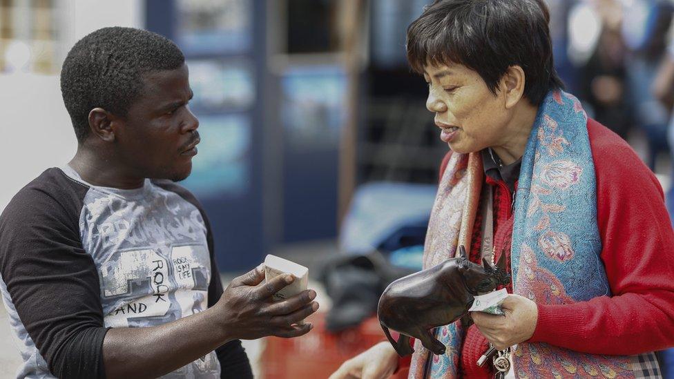 A vendor and tourist haggling in Hout Bay, South Africa - Thursday 24 November 2016