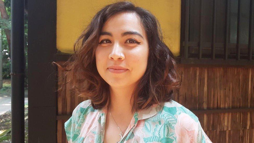 Selfie of Clara, pictured with curly hair, a nose-ring and a floral shirt