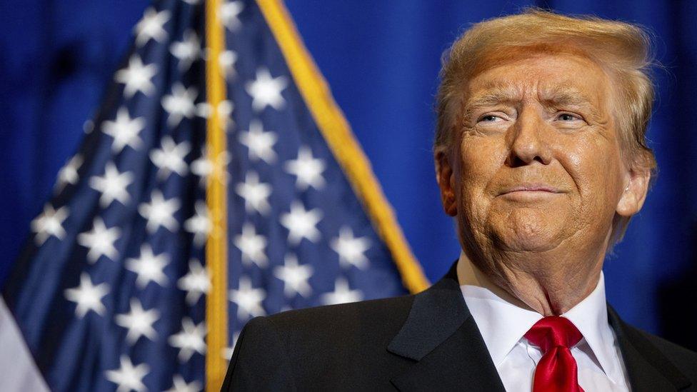 donald trump smiling in front of the us flag