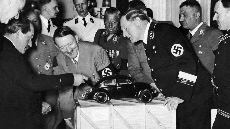 Adolf Hitler looks at a model of the Volkswagen car. He is with the designer Ferdinand Porsche (left)