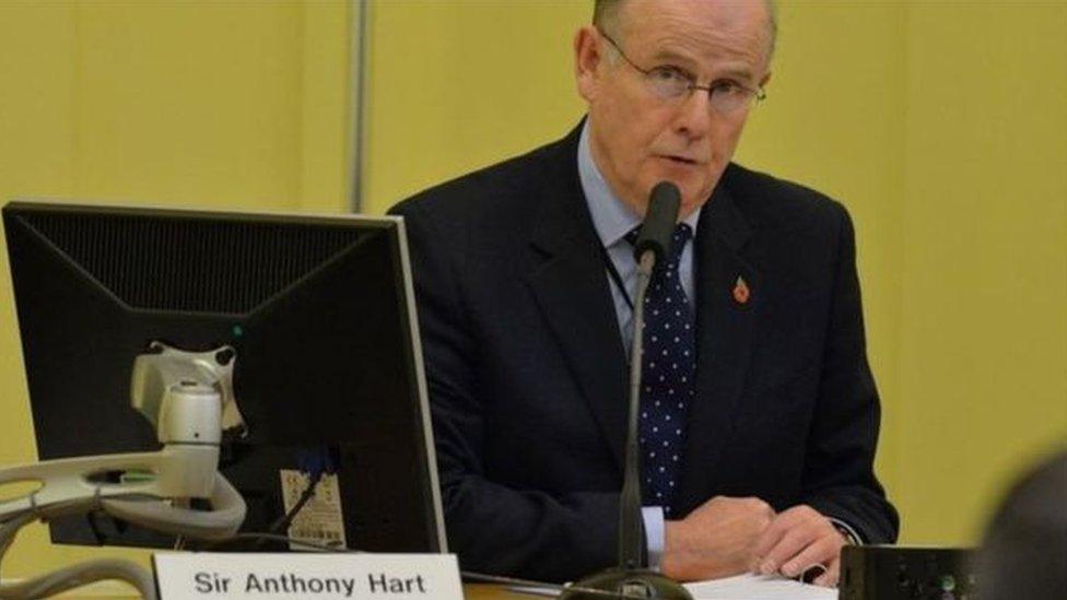 Sir Anthony Hart sits at a desk